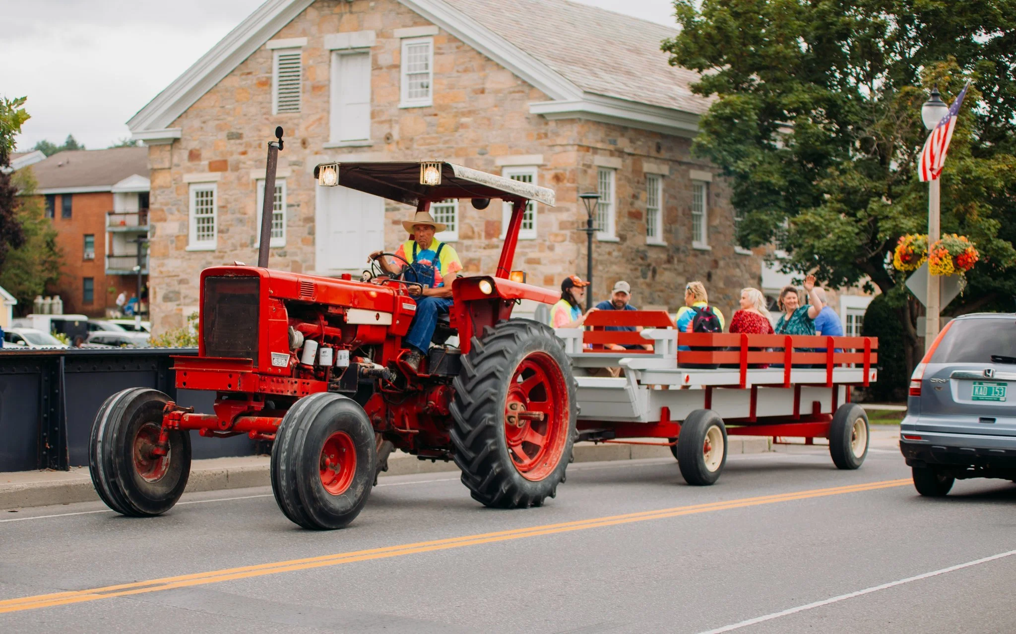 A red tractor pulling a float with people on it during a parade on a city street.