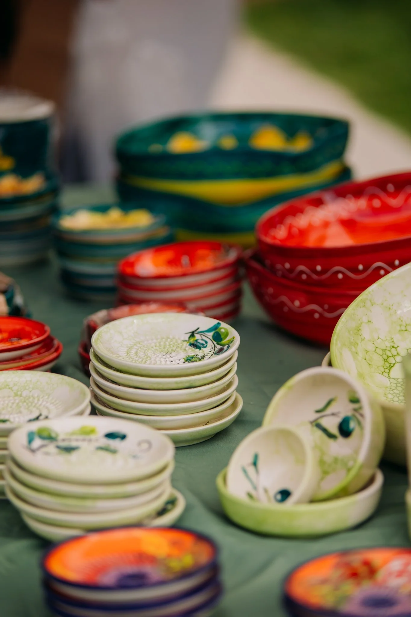 Colorful ceramic bowls stacked on a table at an outdoor market.