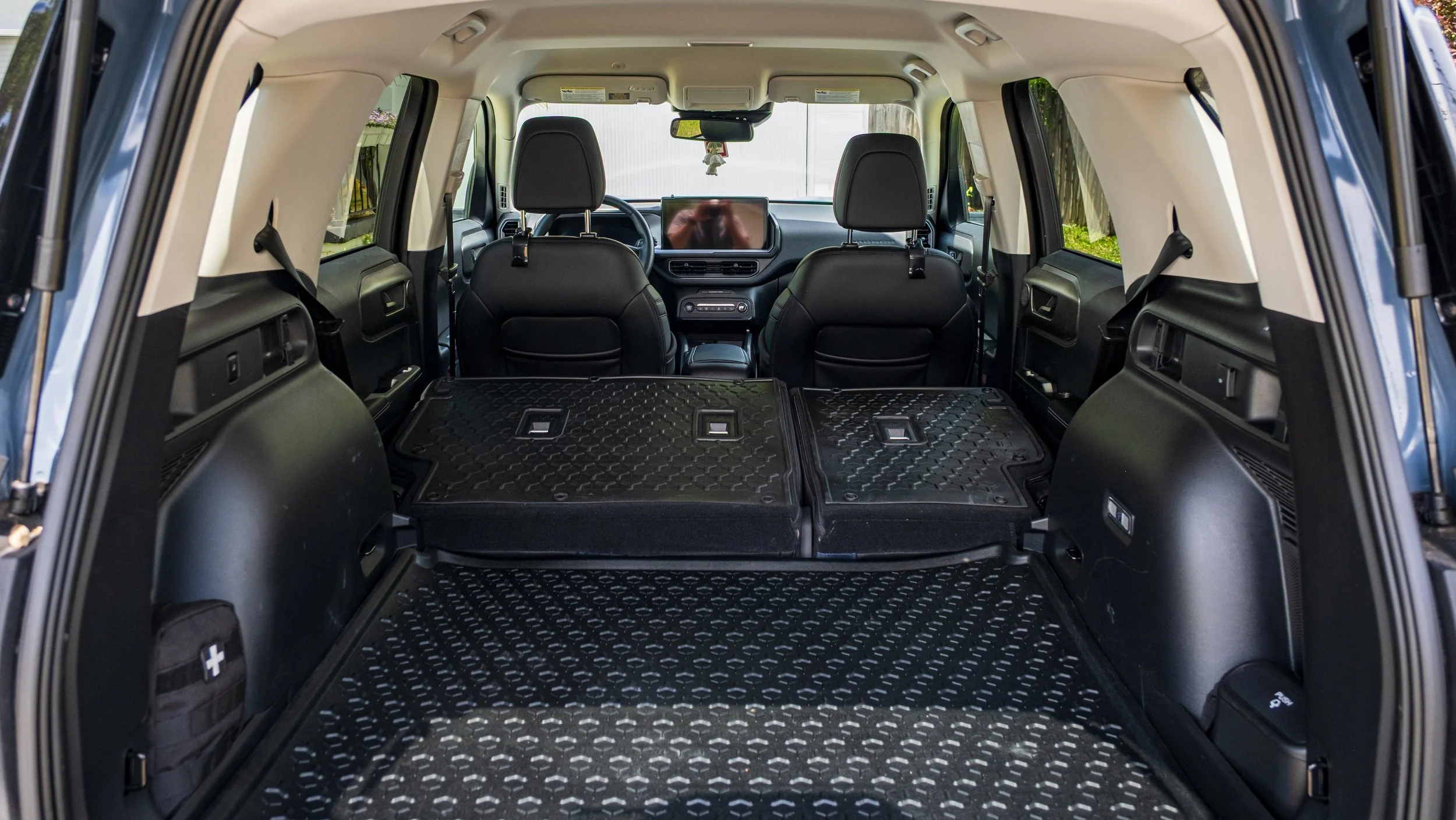 The interior of an SUV with the rear seats folded down, spacious cargo area, black seats, and a dashboard with a large screen.