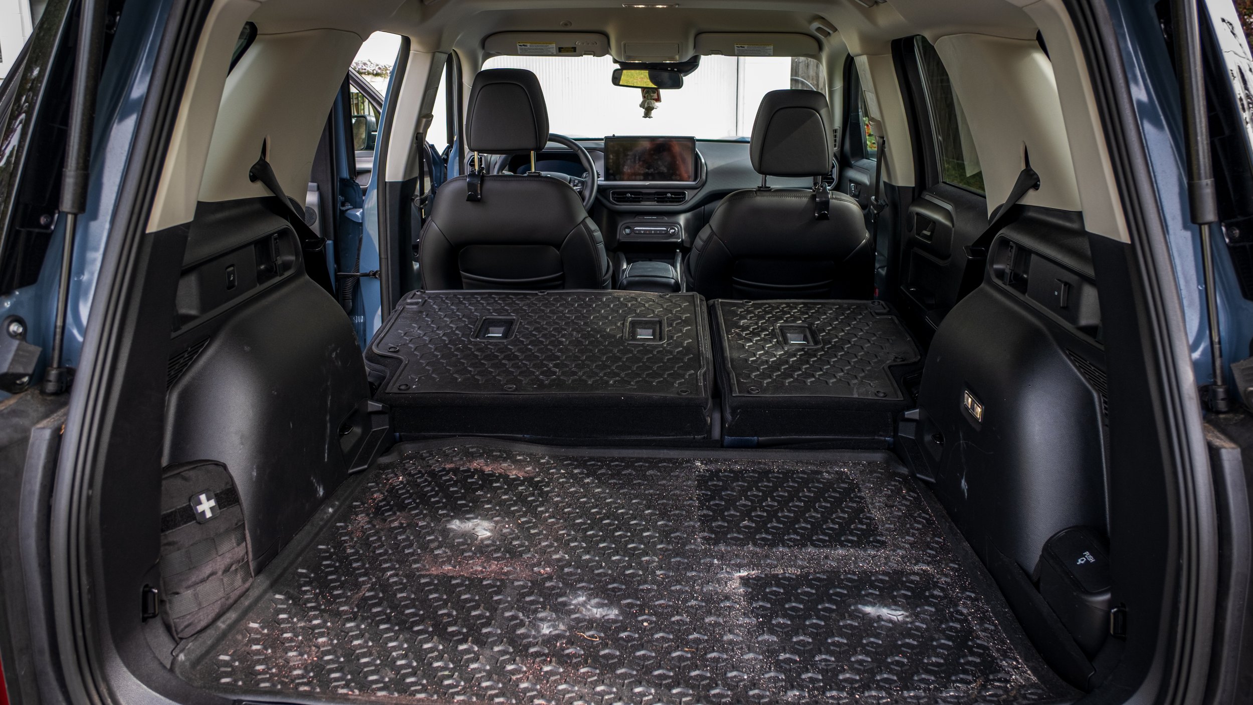 The image shows the interior of an SUV with the rear seats folded down, creating a large cargo space with rubber mats on the floor and seat backs.