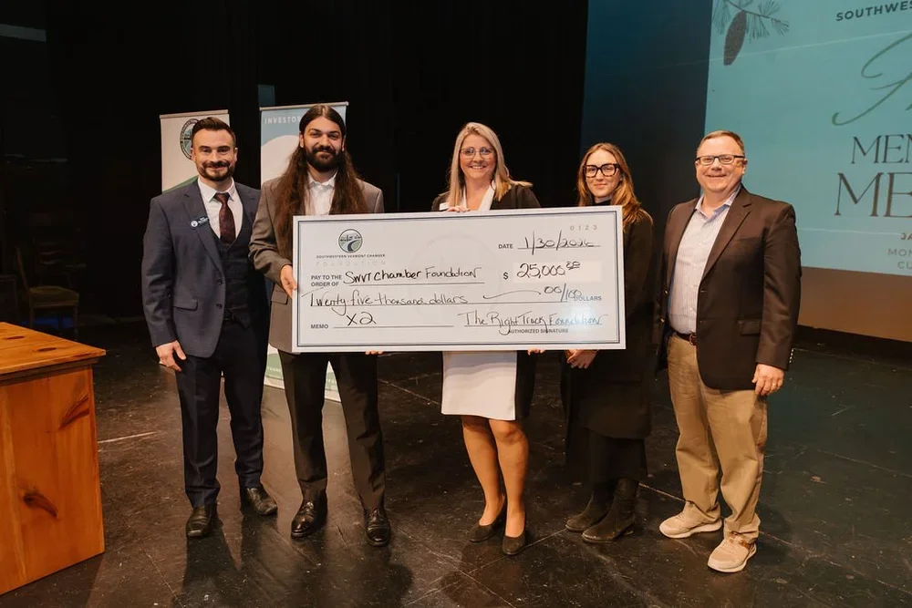 Group of five people on a stage holding a large ceremonial check for $25,000 made out to the Southwest Chamber Foundation.