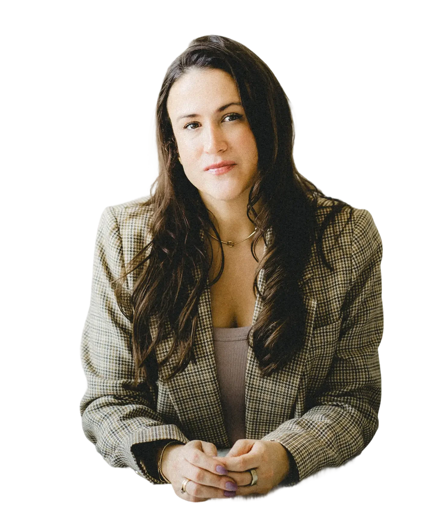 A woman with long dark hair, wearing a checkered blazer and a necklace, sitting with her hands clasped together.