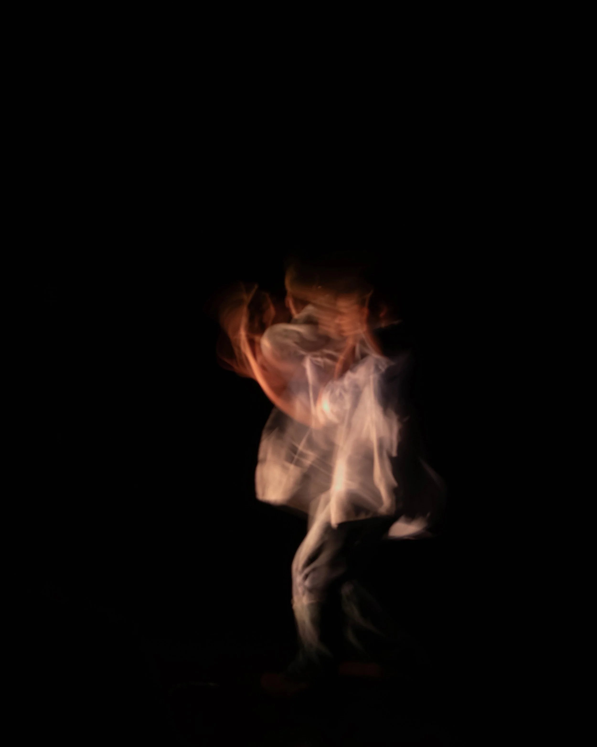 A person in a dark environment is holding fire and performing a fire dance or fire spinning act.