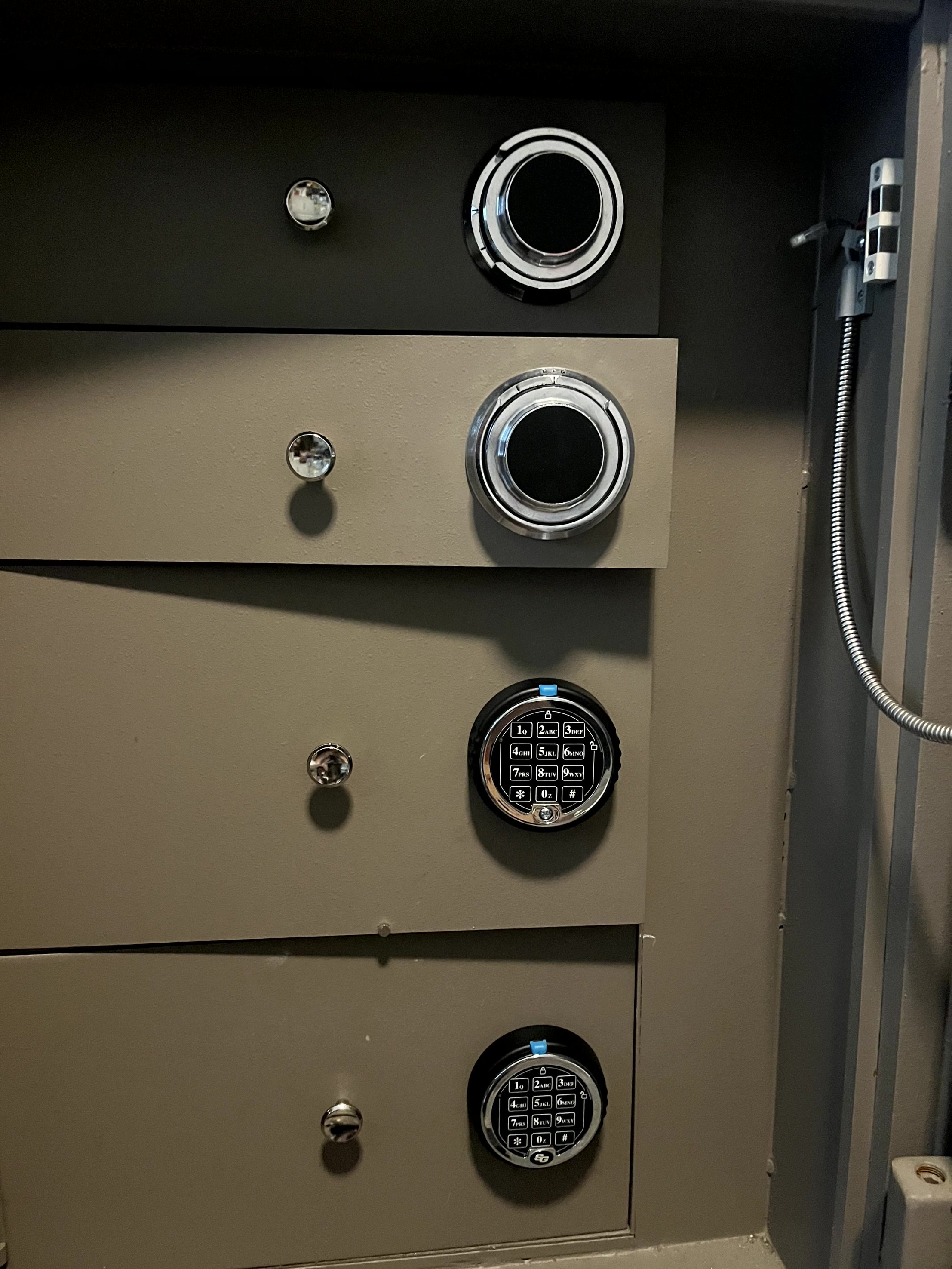 A bank vault with gray and black lockers, some of which have electronic keypads for security.