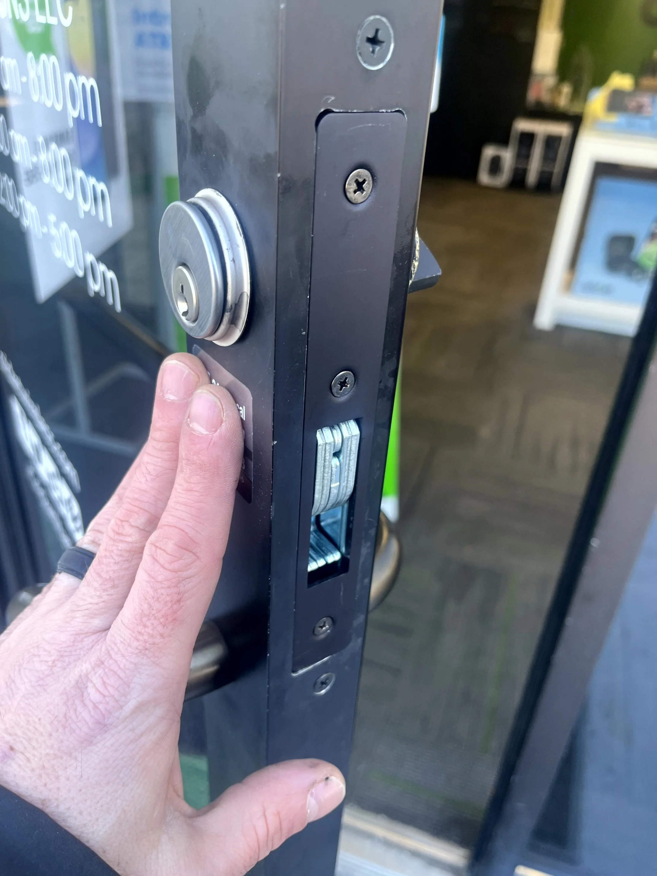 Close-up of a person locking a glass door, holding a key in front of a keypad lock with a coin mechanism in the background.