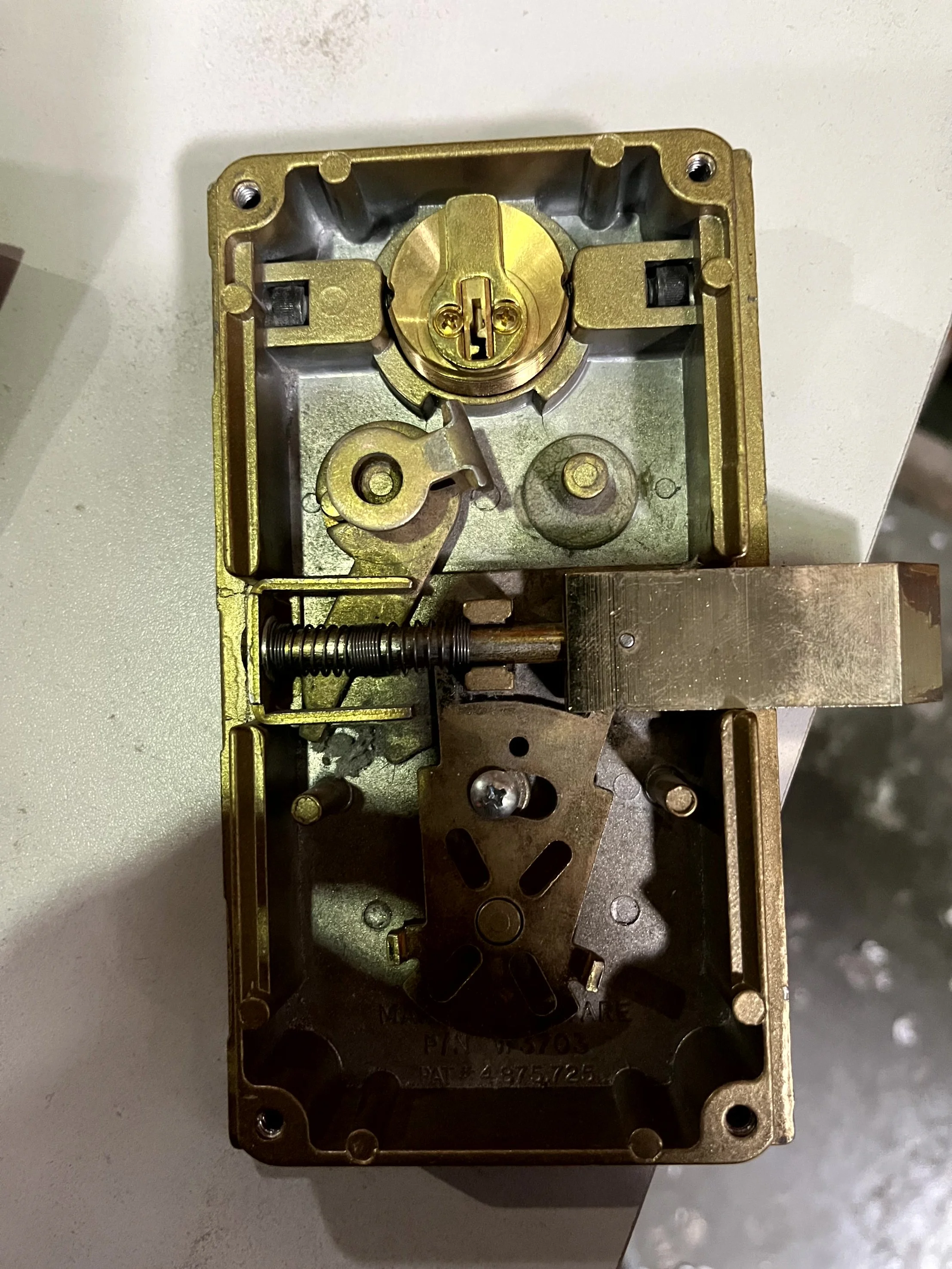 Close-up of an open mechanical lock mechanism with metal components and a spring.