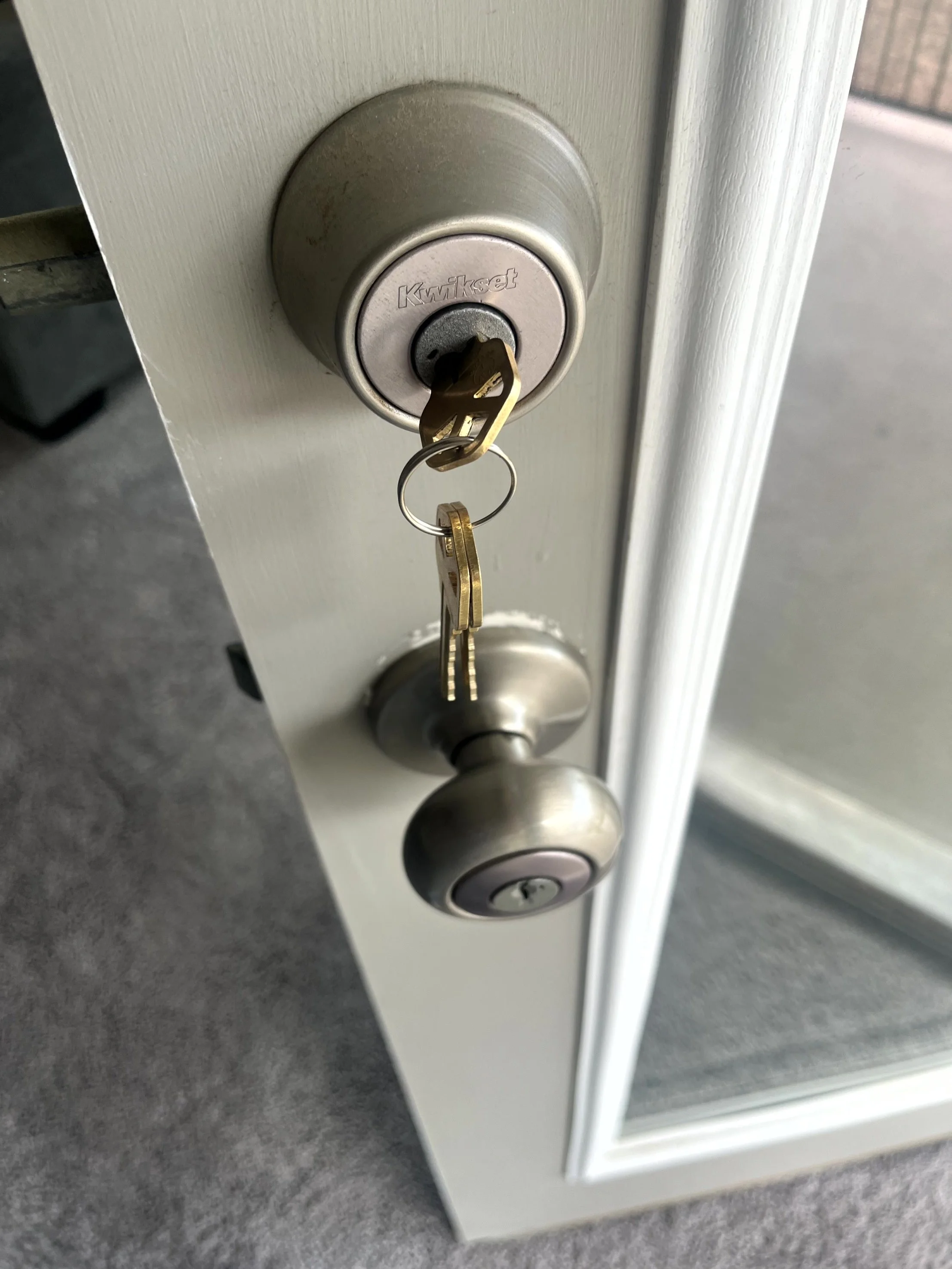 Close-up of a silver doorknob and a deadbolt lock with a key inserted.