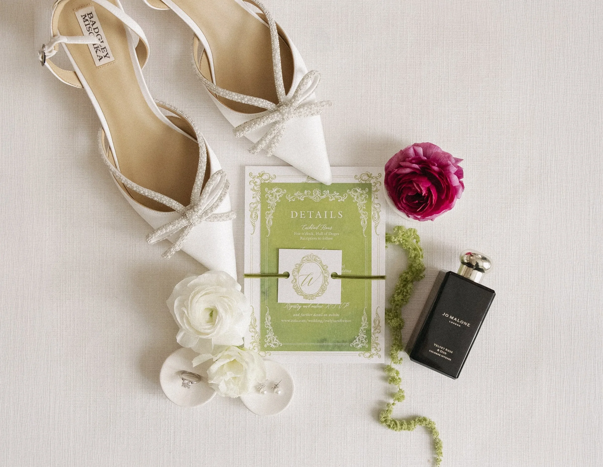 Wedding flatlay with shoes, a wedding invitation, a pink and a white flower, a bottle of Jo Malone perfume, at the Davenport Hotel in Spokane, Washington