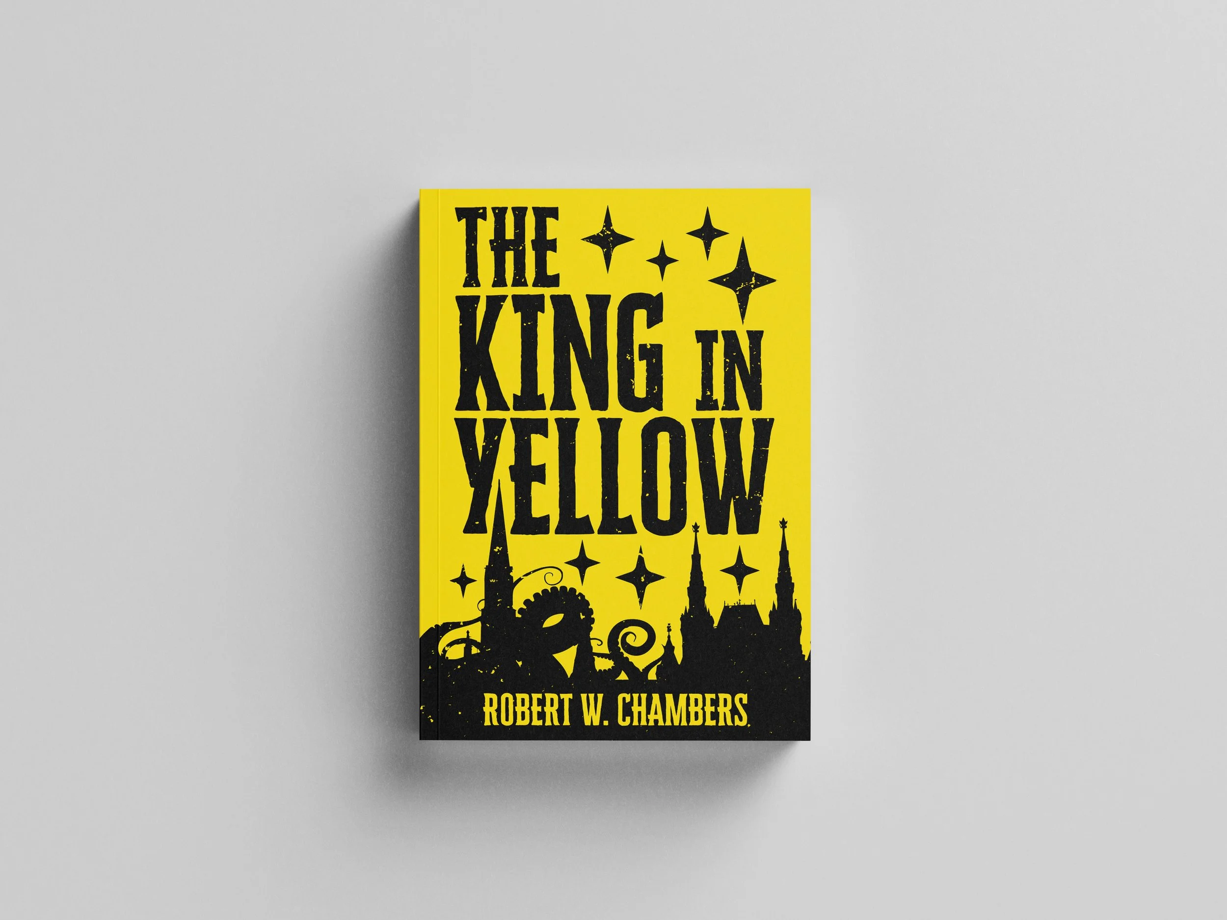 Book titled 'The King in Yellow' by Robert W. Chambers with a yellow cover featuring black text and illustrations of a city skyline and stars.