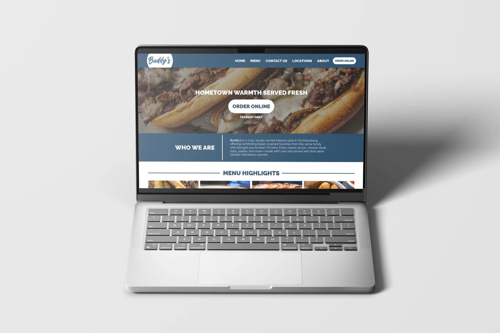 Silver laptop displaying a restaurant website on a gray table with gray background