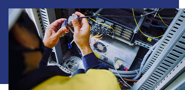 Technician working inside a network server rack, managing cables and equipment