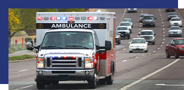 An ambulance driving on a multi-lane road surrounded by other vehicles