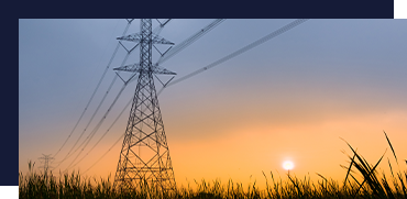 Sunset sky with power lines and a tall electrical pylon in the foreground, grassy field below.