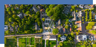 Aerial view of a residential neighborhood with trees, houses, and a grid of streets and sidewalks.