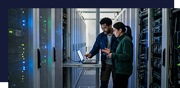 Two technicians working in a data center with server racks and network equipment.