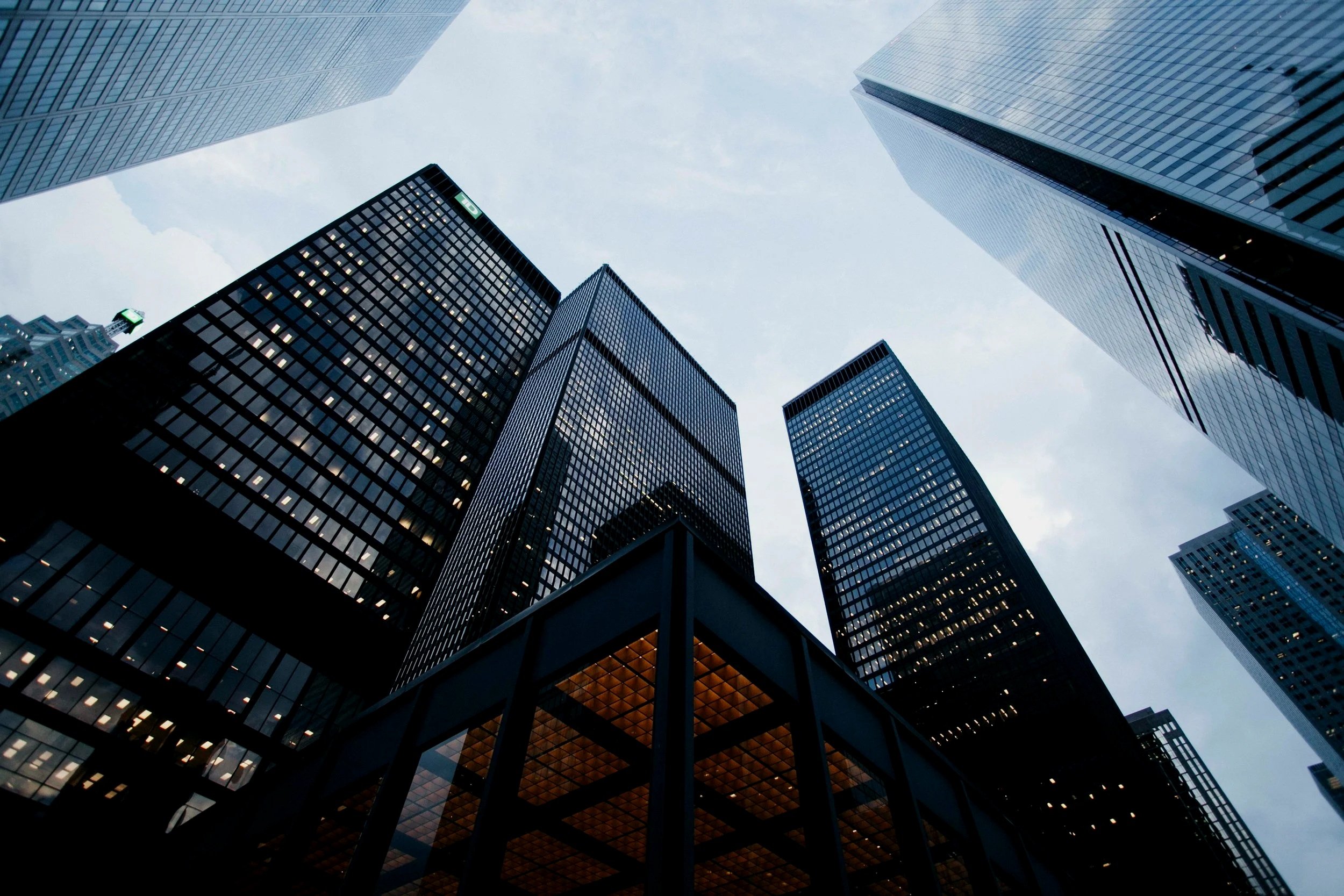 Photo of tall modern skyscrapers seen from below, with glass facades reflecting the sky.