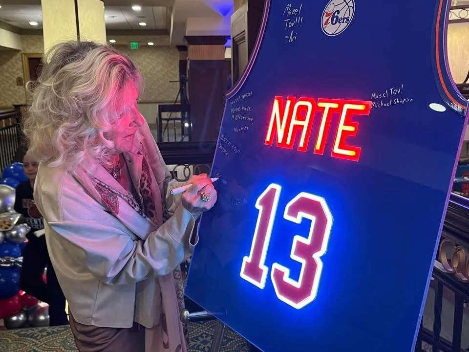 Blue 76ers basketball jersey sign-in board with bold red neon accents.
