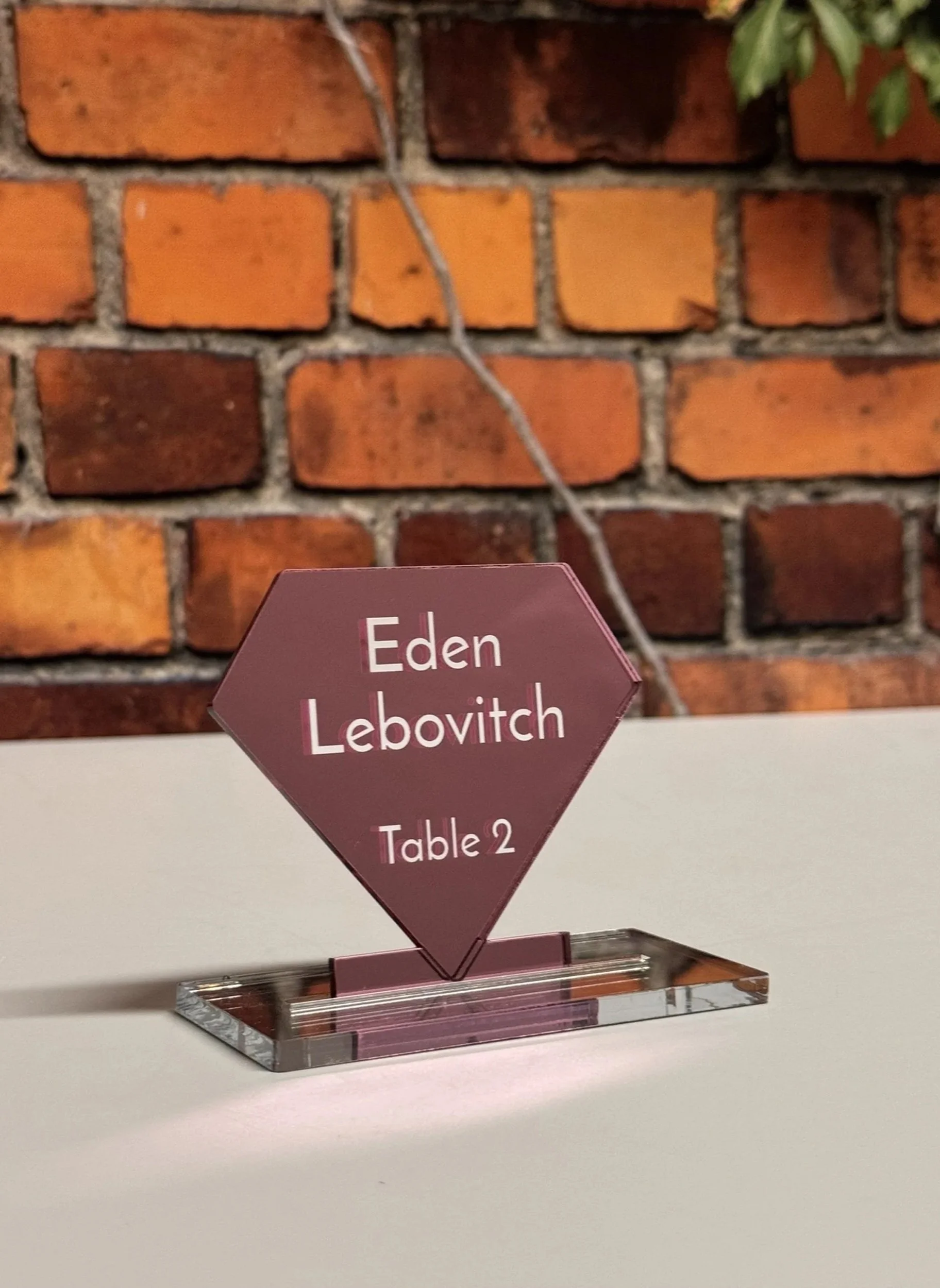 Pink mirrored acrylic, diamond-shaped escort card. 