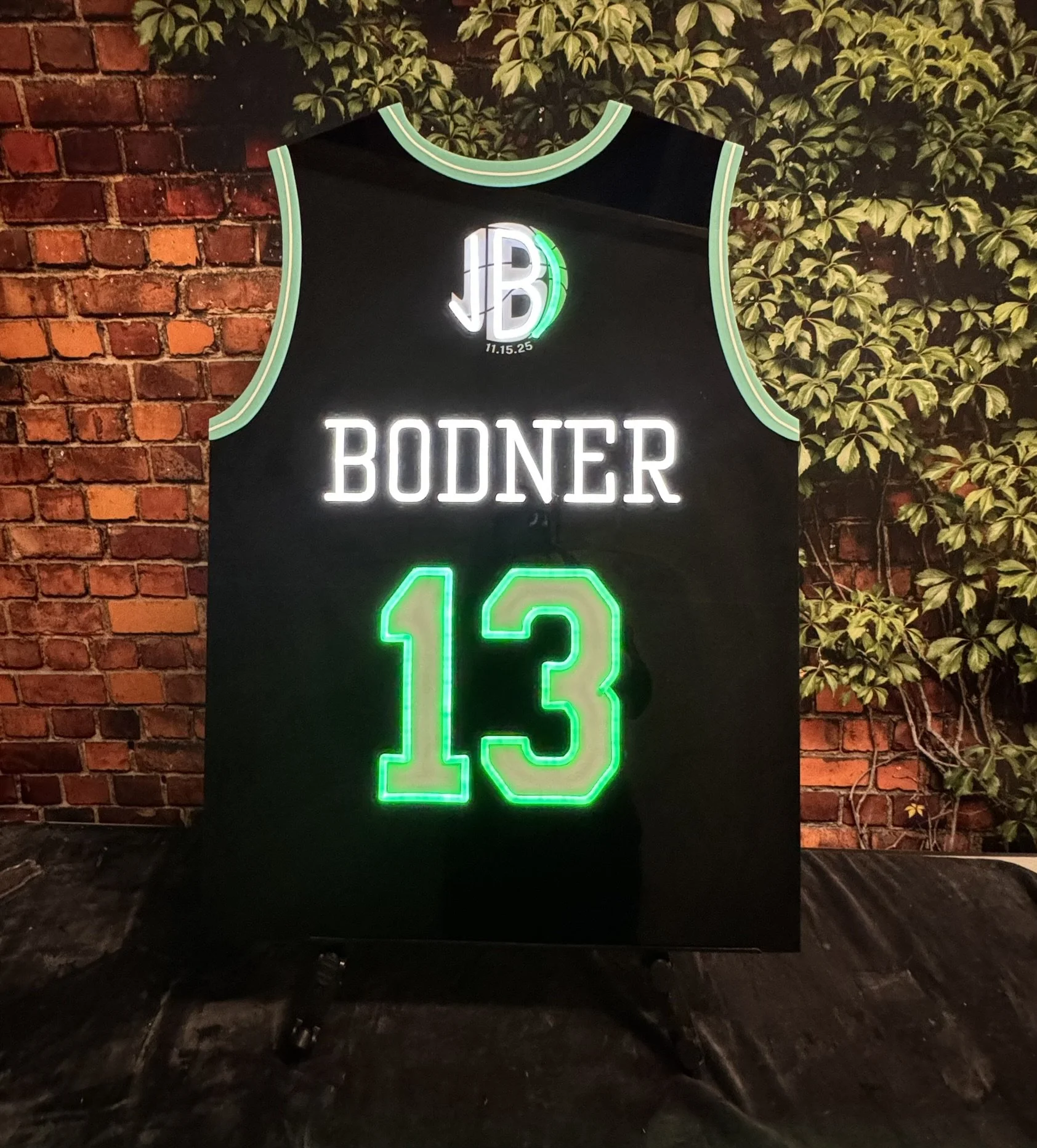 Black custom basketball jersey with green and white detailing. 