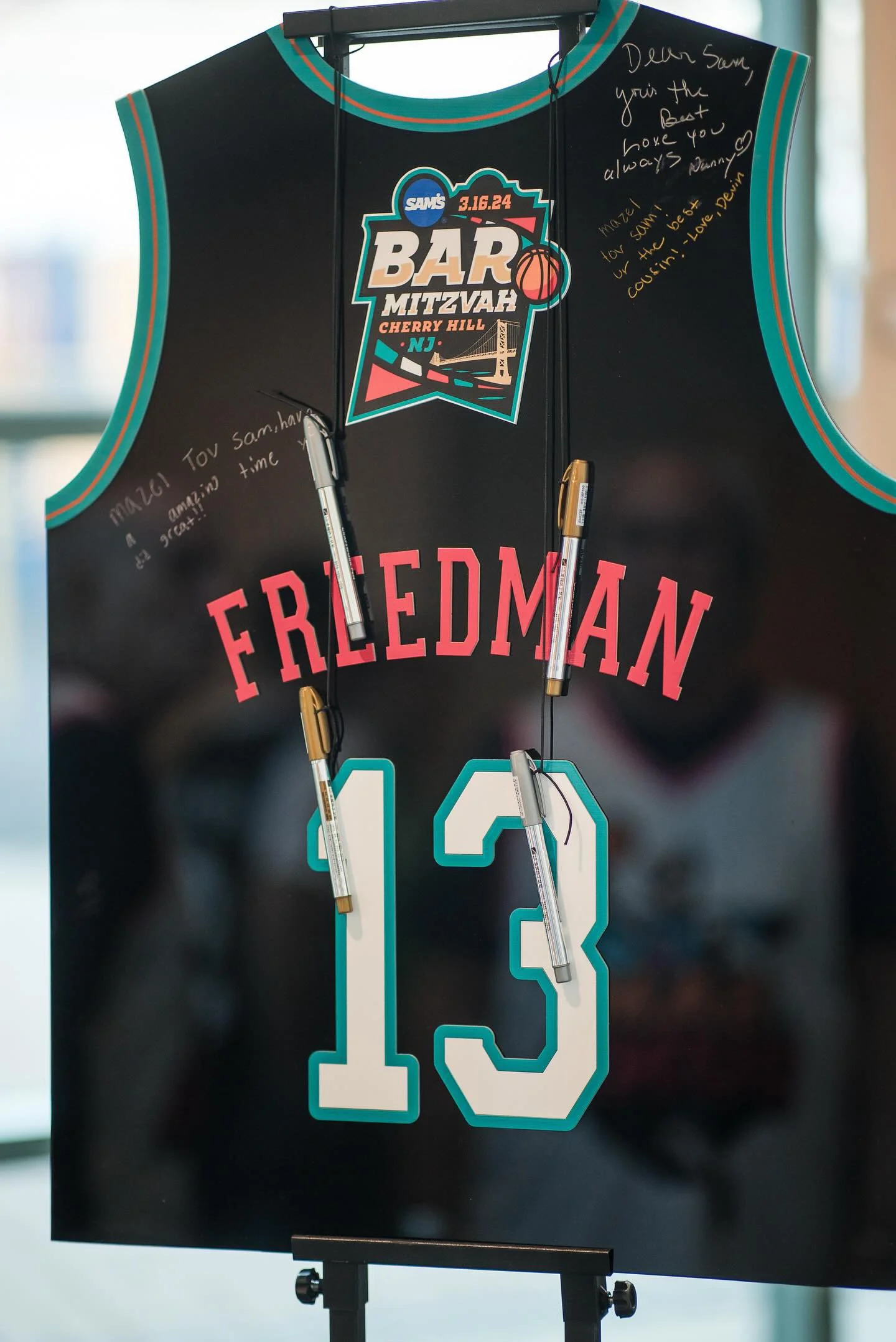Custom black basketball jersey sign-in board with teal and red accents.