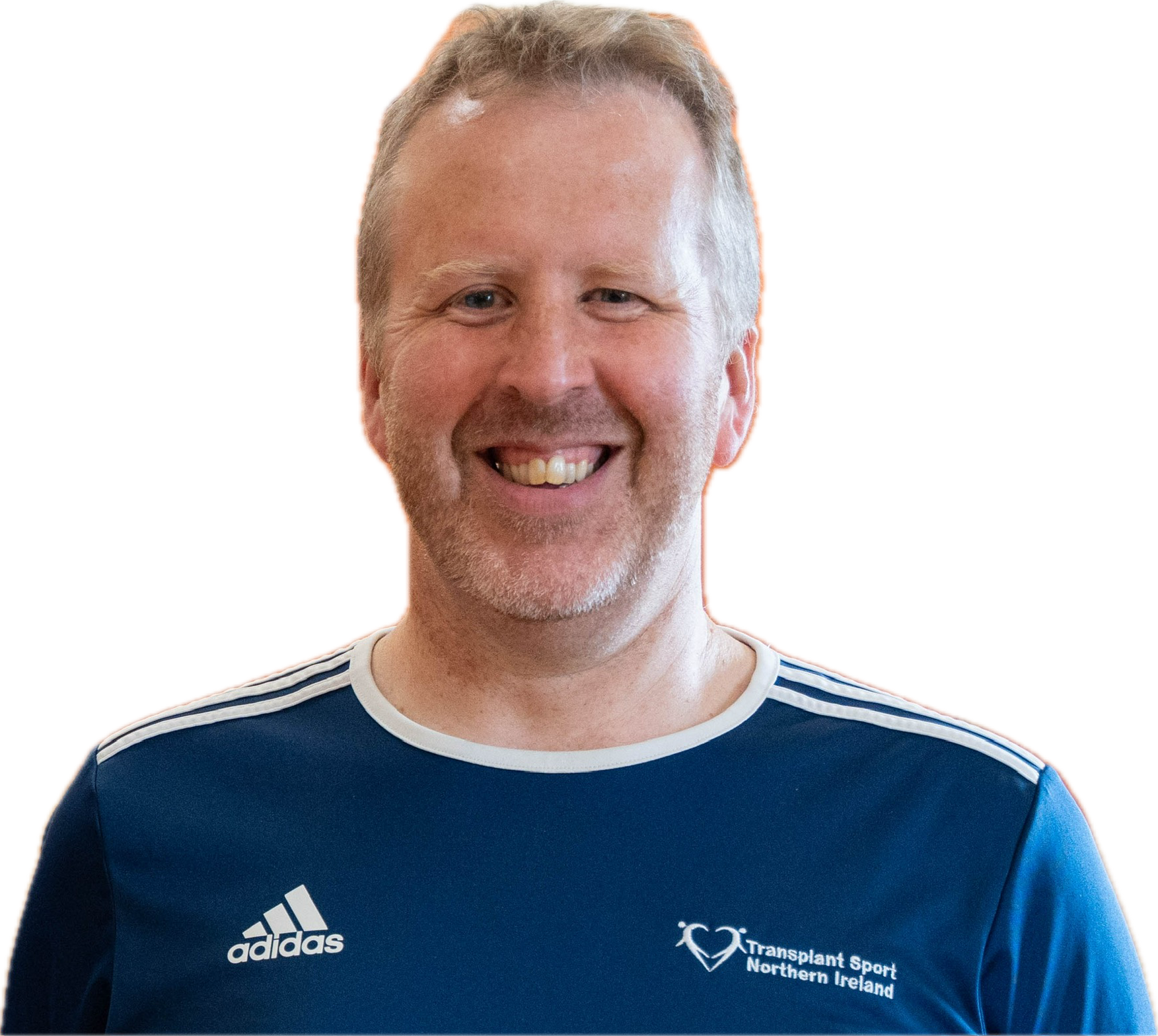 A smiling man with short, light-colored hair and a beard, wearing a blue sports shirt with the Transplant Sport Northern Ireland logo.