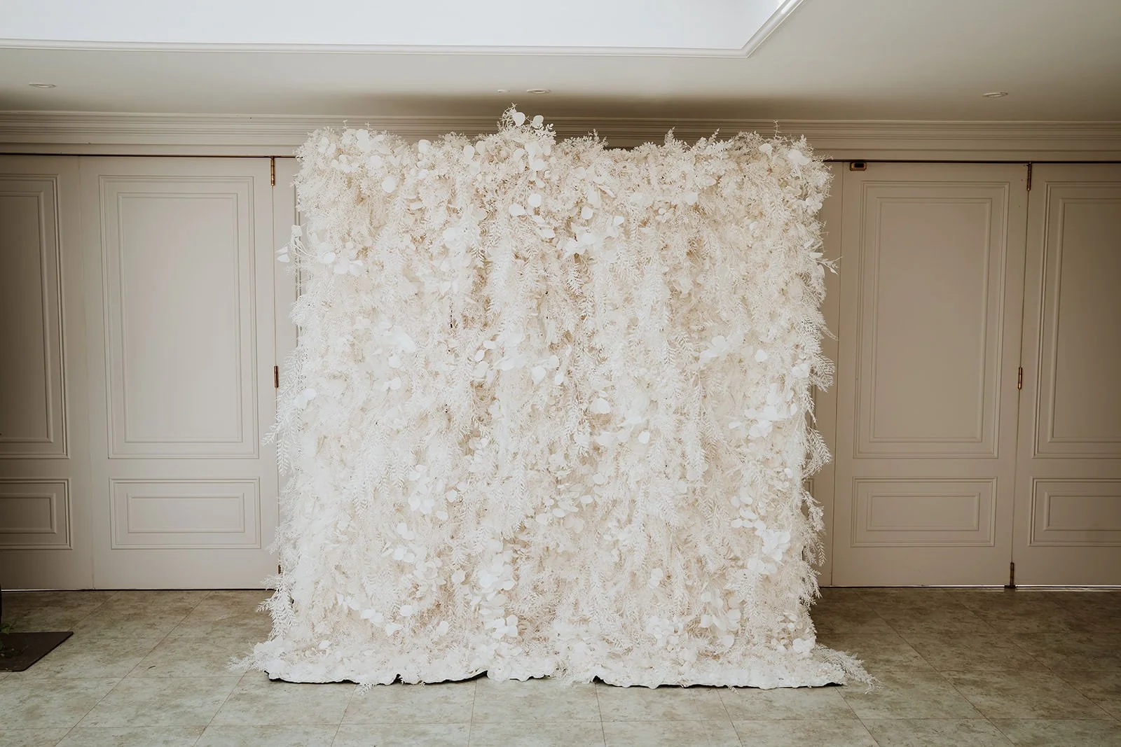 White floral backdrop in a room with closed white doors and tiled floor.