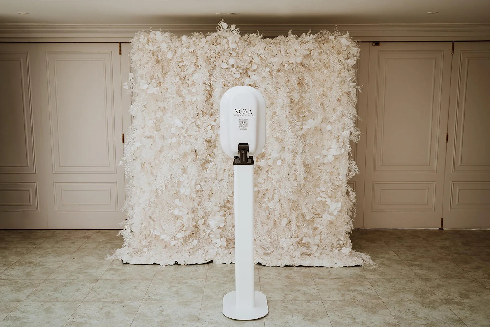 White floral backdrop with a photo booth in front.
