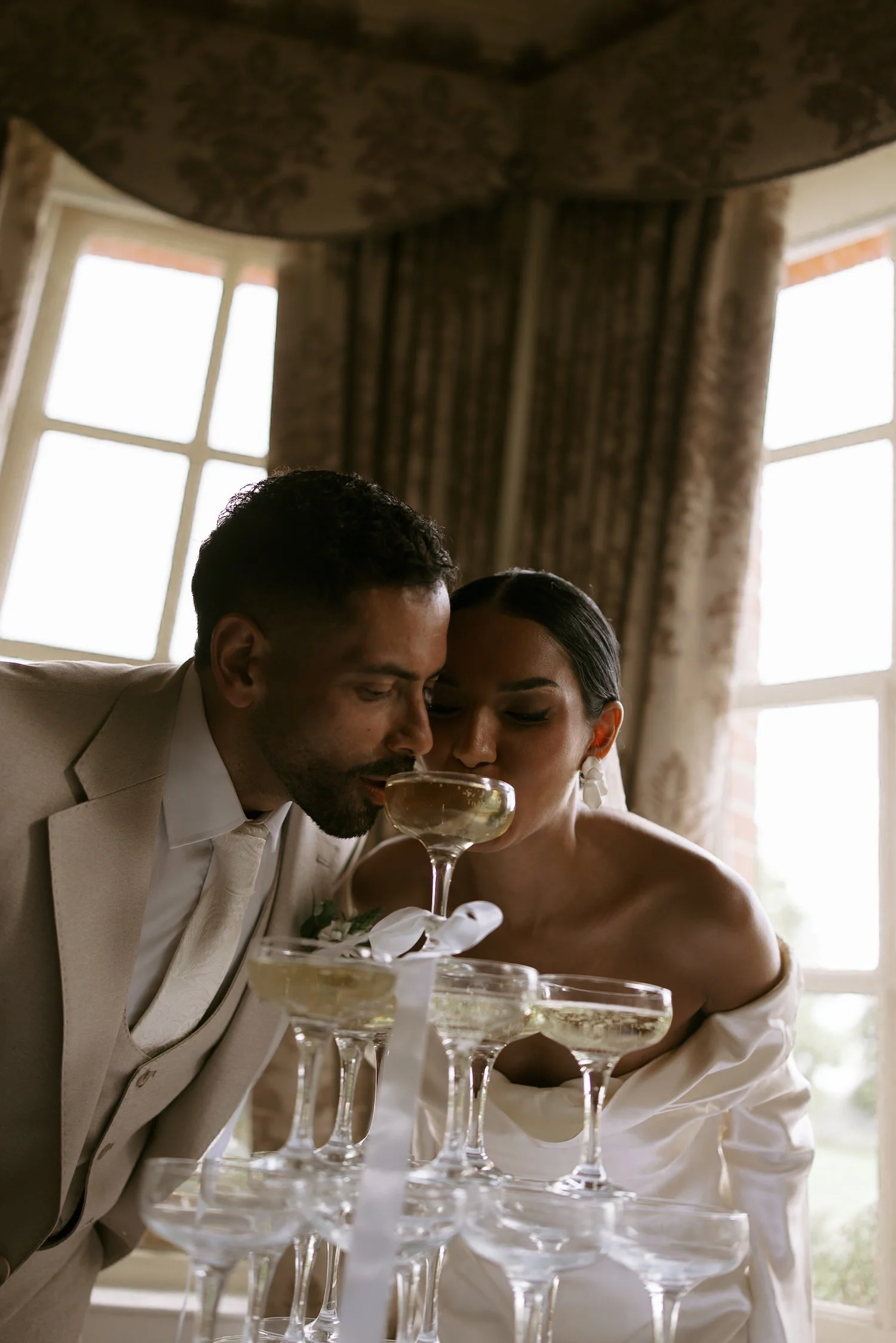 A man and woman dressed in formal attire sharing a drink at a celebration, with a layered cocktail glass arrangement in front of them.
