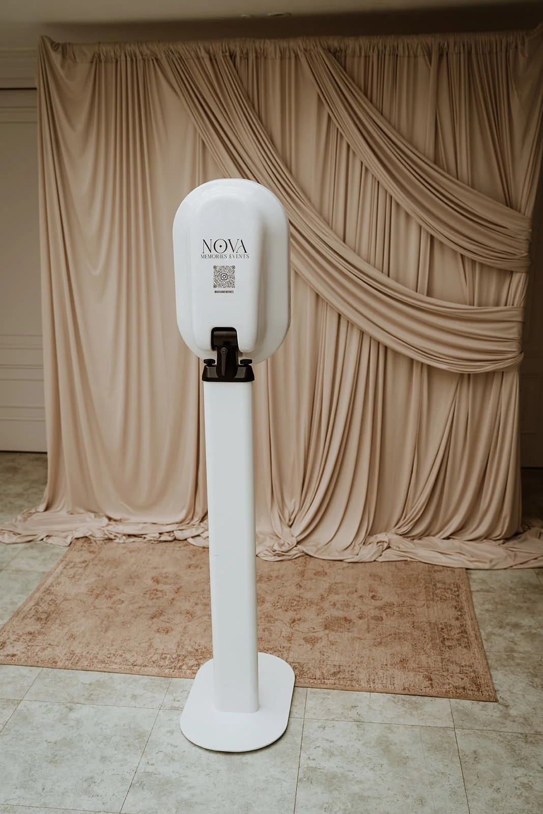 a photo booth with a backdrop of beige draped curtains at an event.