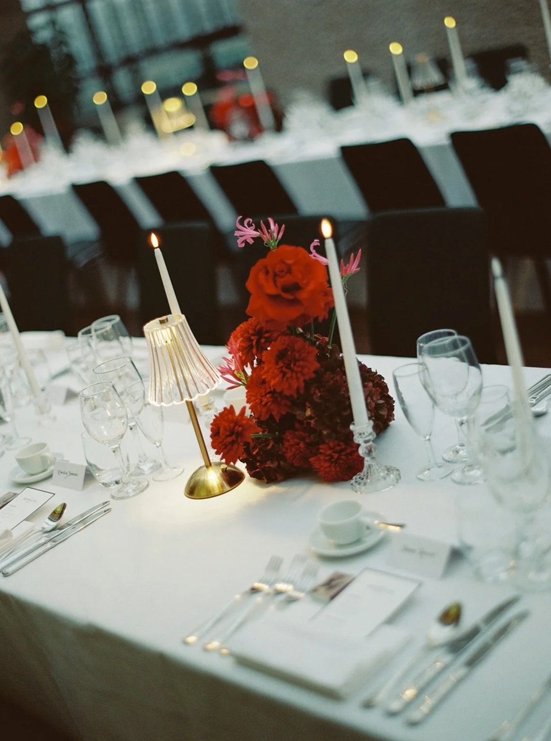 A table set for a formal event with a floral centerpiece, candles, and glassware.