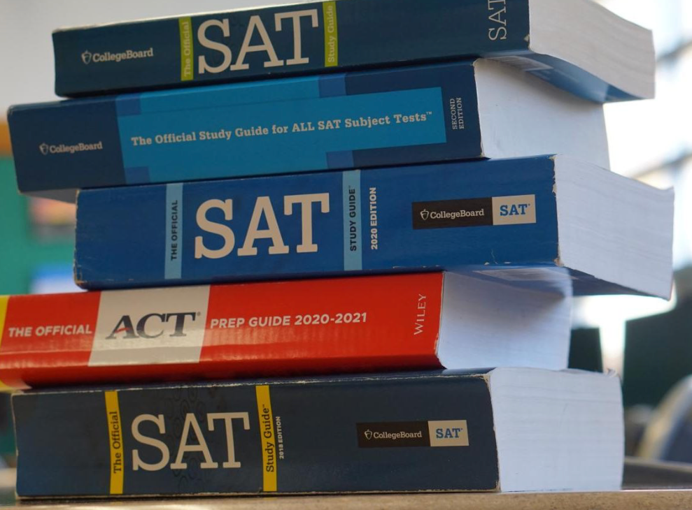 Stack of five college test prep books, including SAT and ACT guides, with visible titles and binding details.