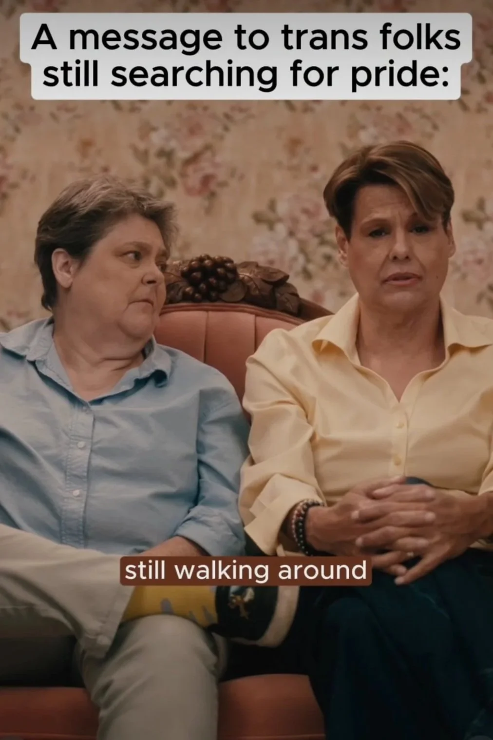 Loving elder trans couple sits on a vintage loveseat with floral backdrop. Text reads, "A message to trans folks still searching for pride". Links to Facebook.