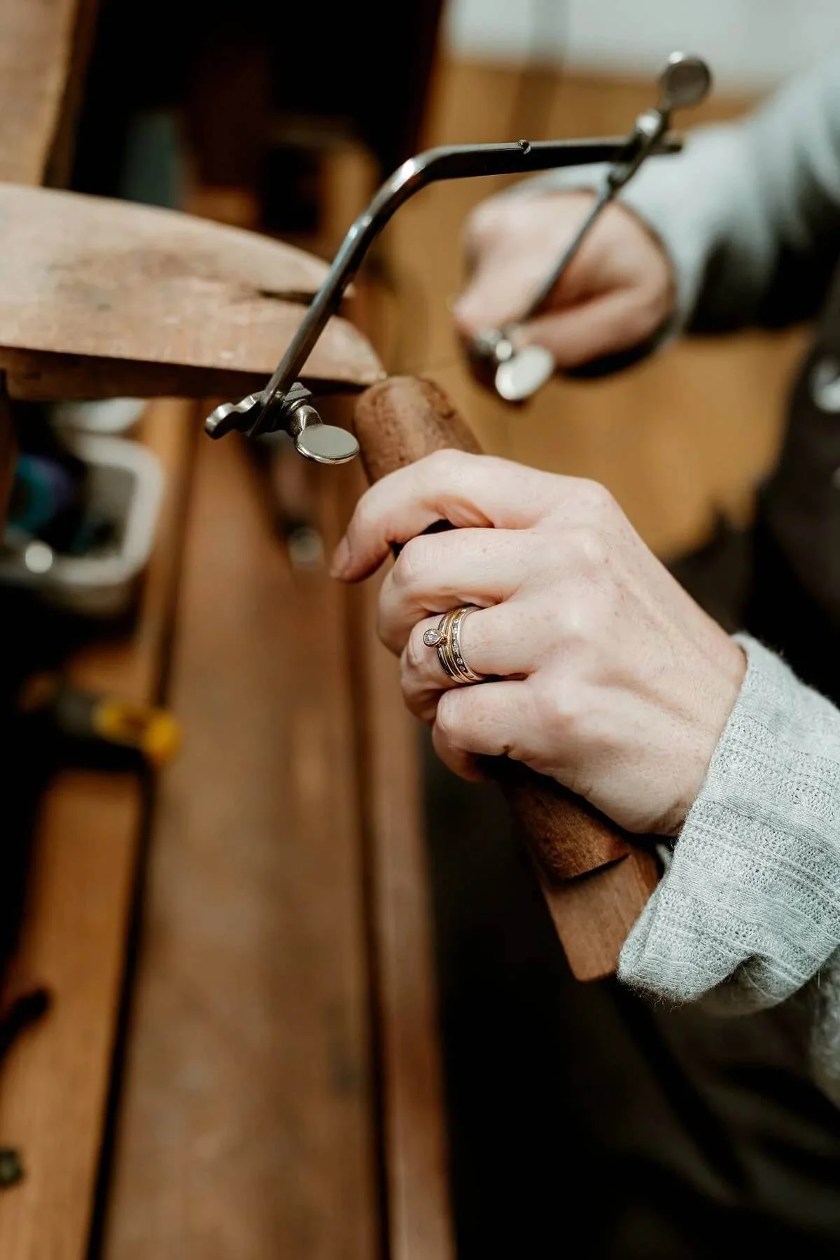 A person using a key saw to cut a wooden piece on a workbench in a workshop.