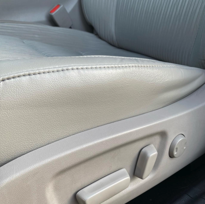 Close-up of a beige leather car seat with adjustment controls visible on the side.