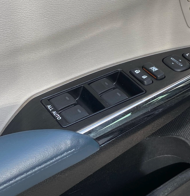 Car door control panel with window switches, lock buttons, and mirror adjustment knob.