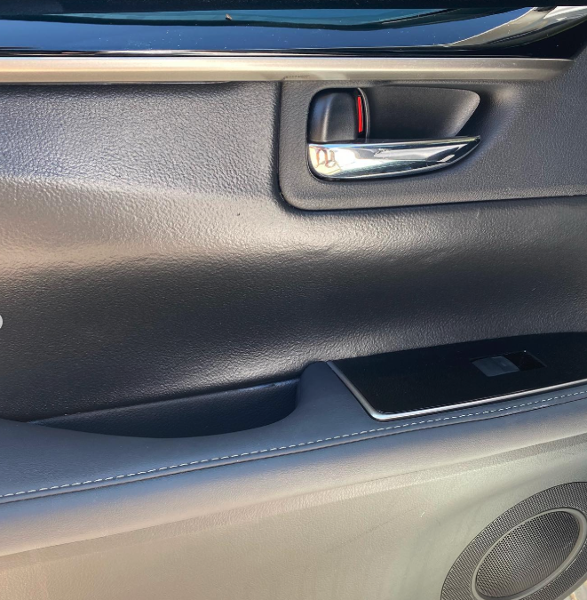 Close-up of a car door interior showing a door handle, lock, and storage compartment.
