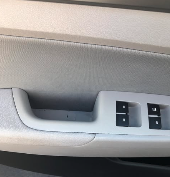 Close-up of a car door panel with window control switches and a small storage compartment.