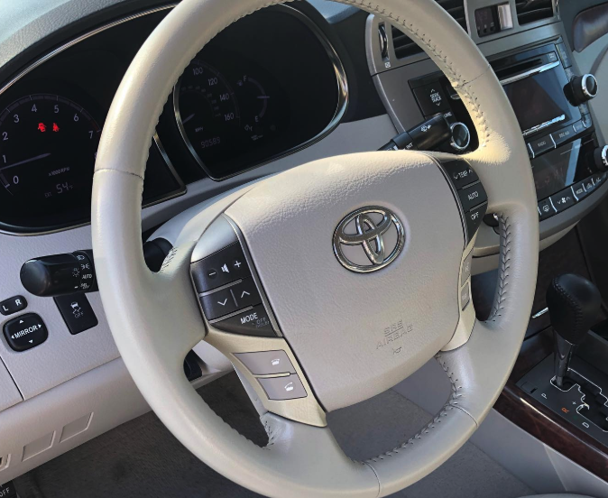 Interior view of a Toyota vehicle dashboard showing steering wheel with Toyota logo, speedometer, and control buttons.