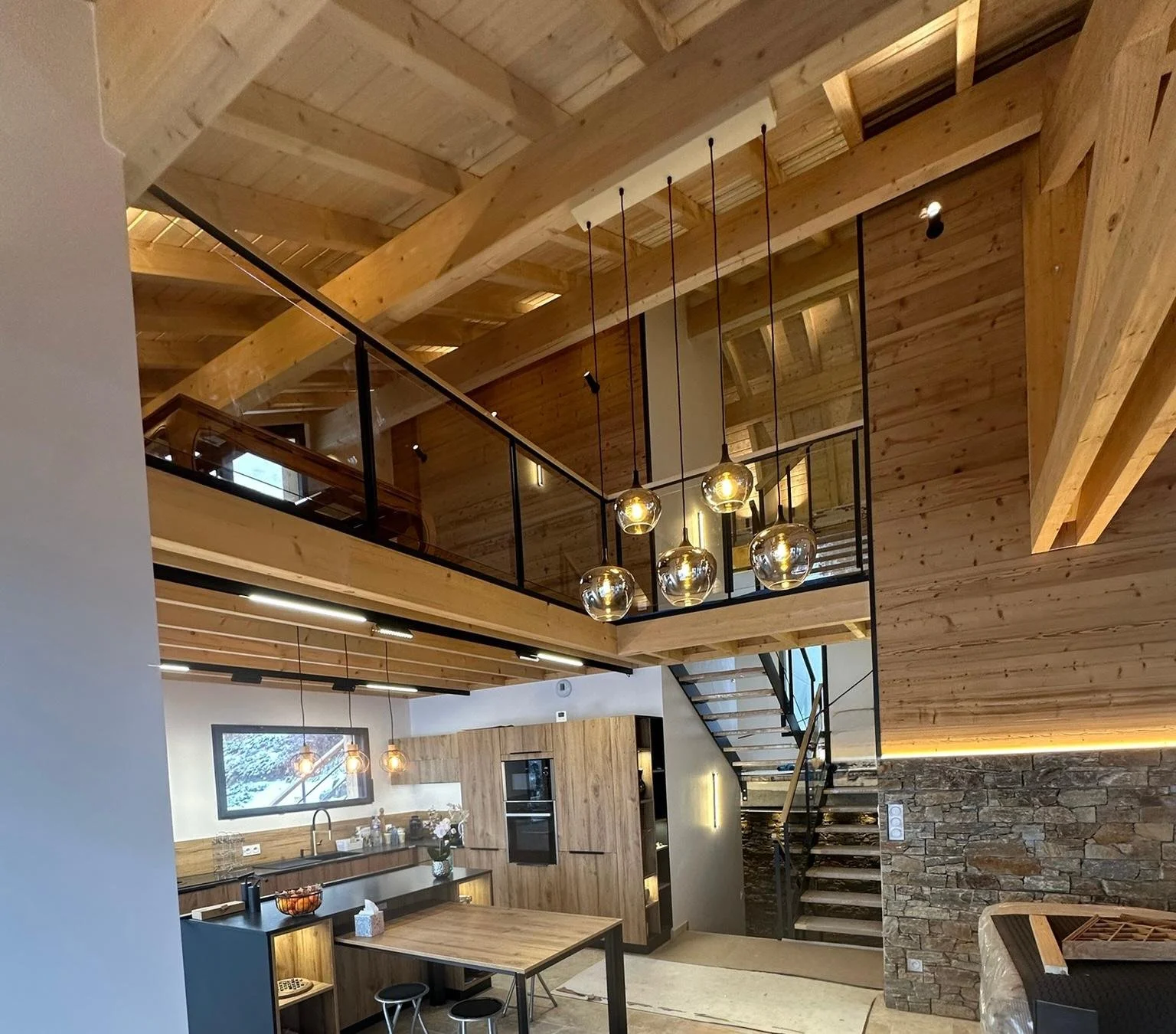 Conception d'éclairages pour une maison en bois avec un plafond en bois, une mezzanine, et un escalier en métal, décoration moderne et chaleureuse.