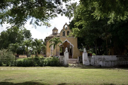 Small colonial chapel with a bell gable set in a leafy green park in Mérida