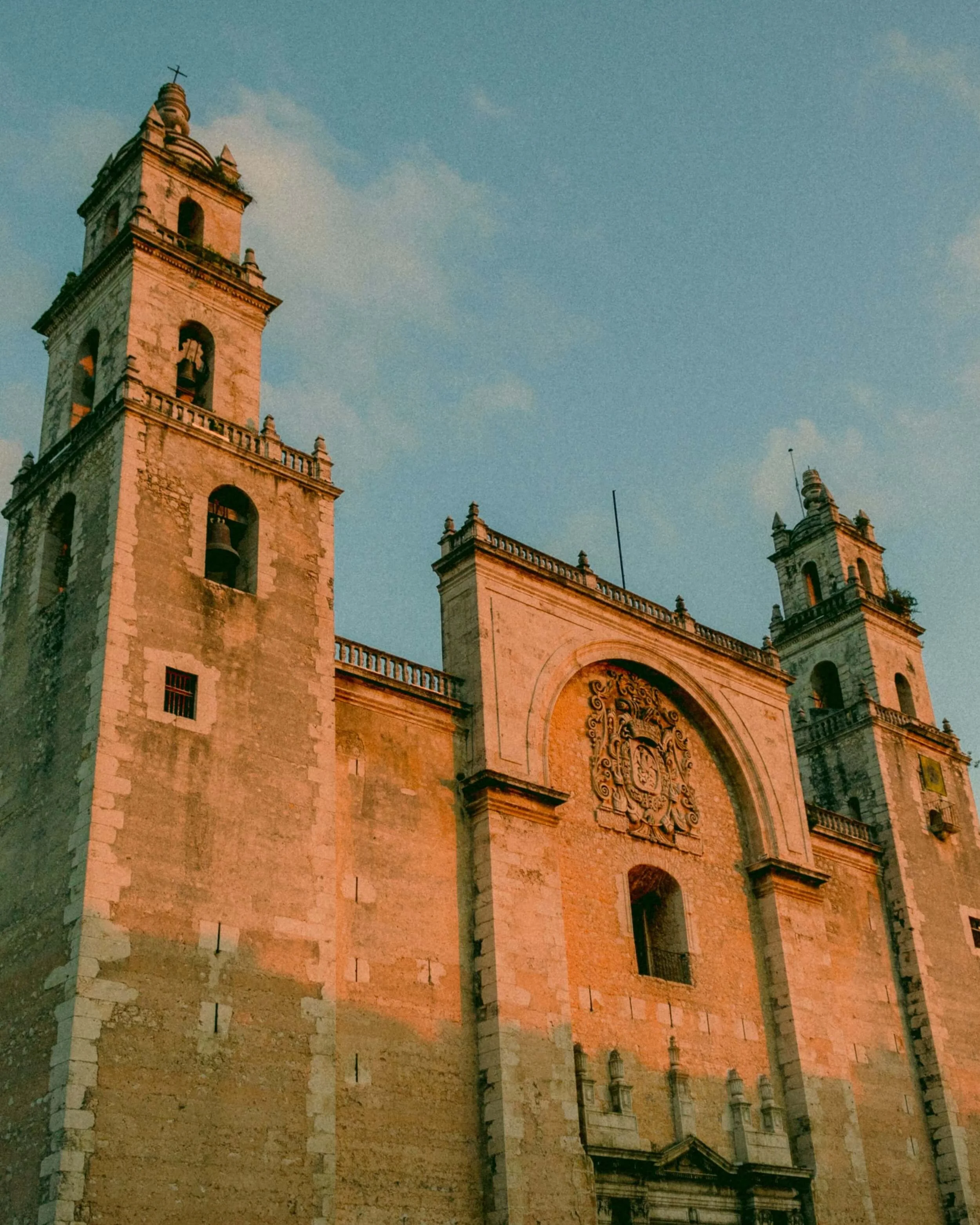 Twin bell towers of Mérida Cathedral glowing orange in the late afternoon sun