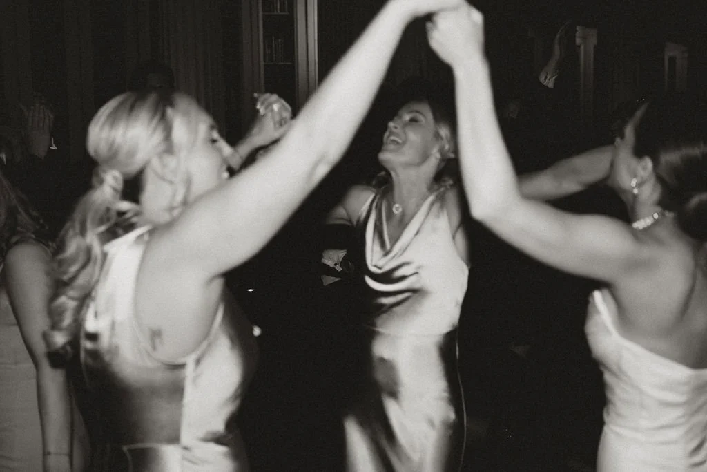 Women dancing and holding hands in a circle at a celebration or party.