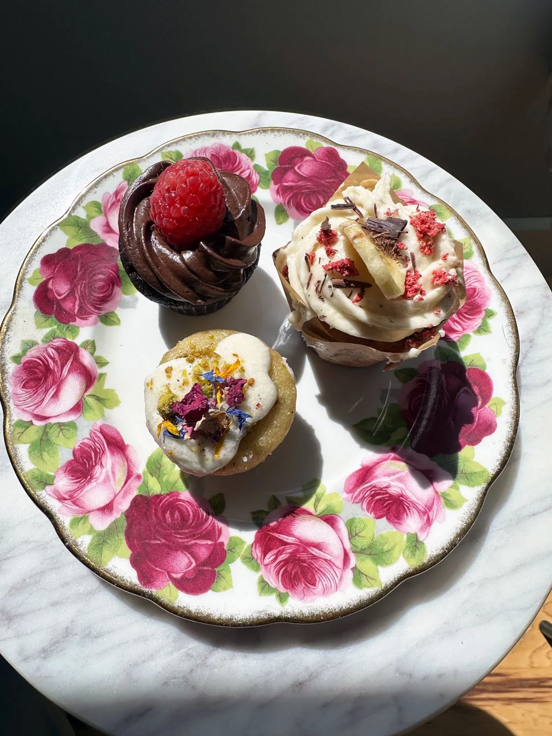 A sample of Sassy Rose's delicious cupcakes on a floral plate with pink roses