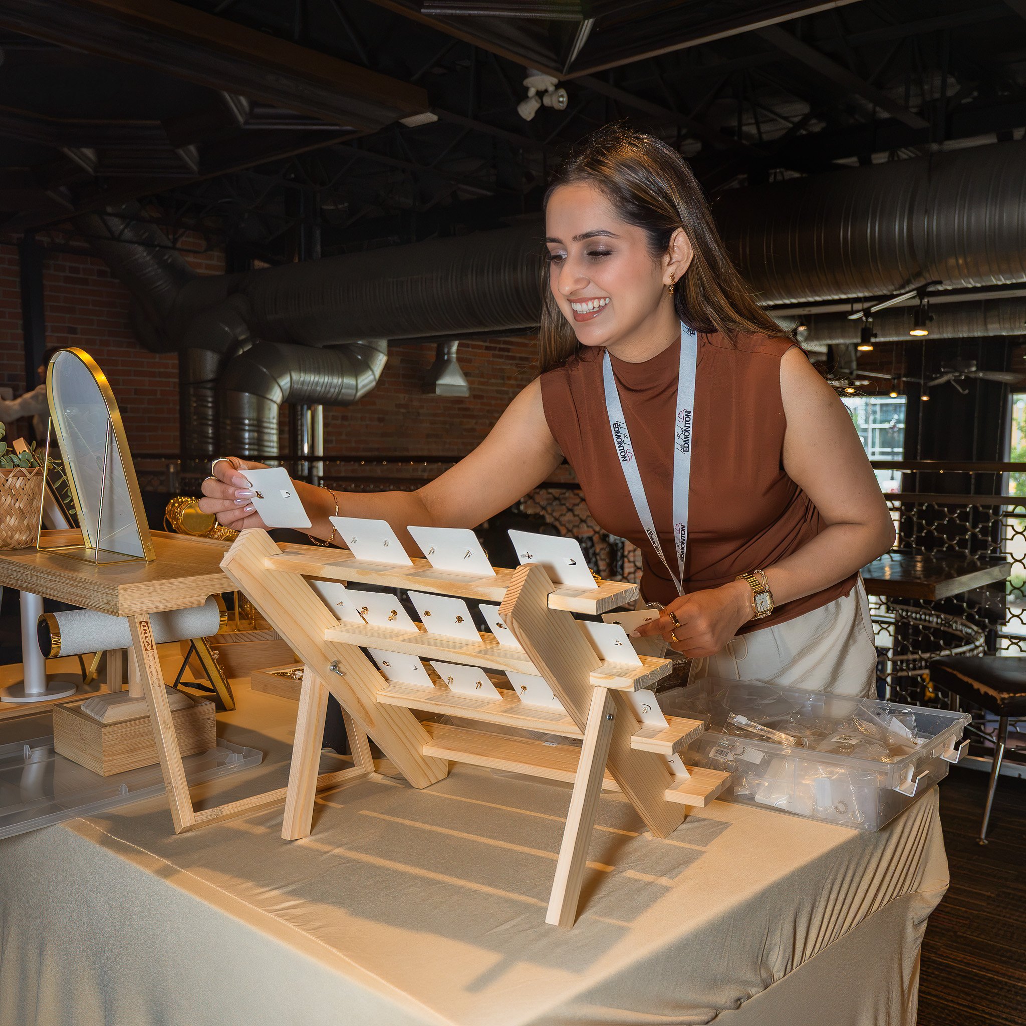 Woman smiling and shopping for jewelry at a display stand in a retail store.