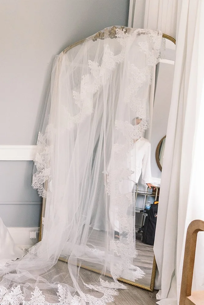 Nikki Golden Photographer takes a photo of brides veil draped over mirror. 