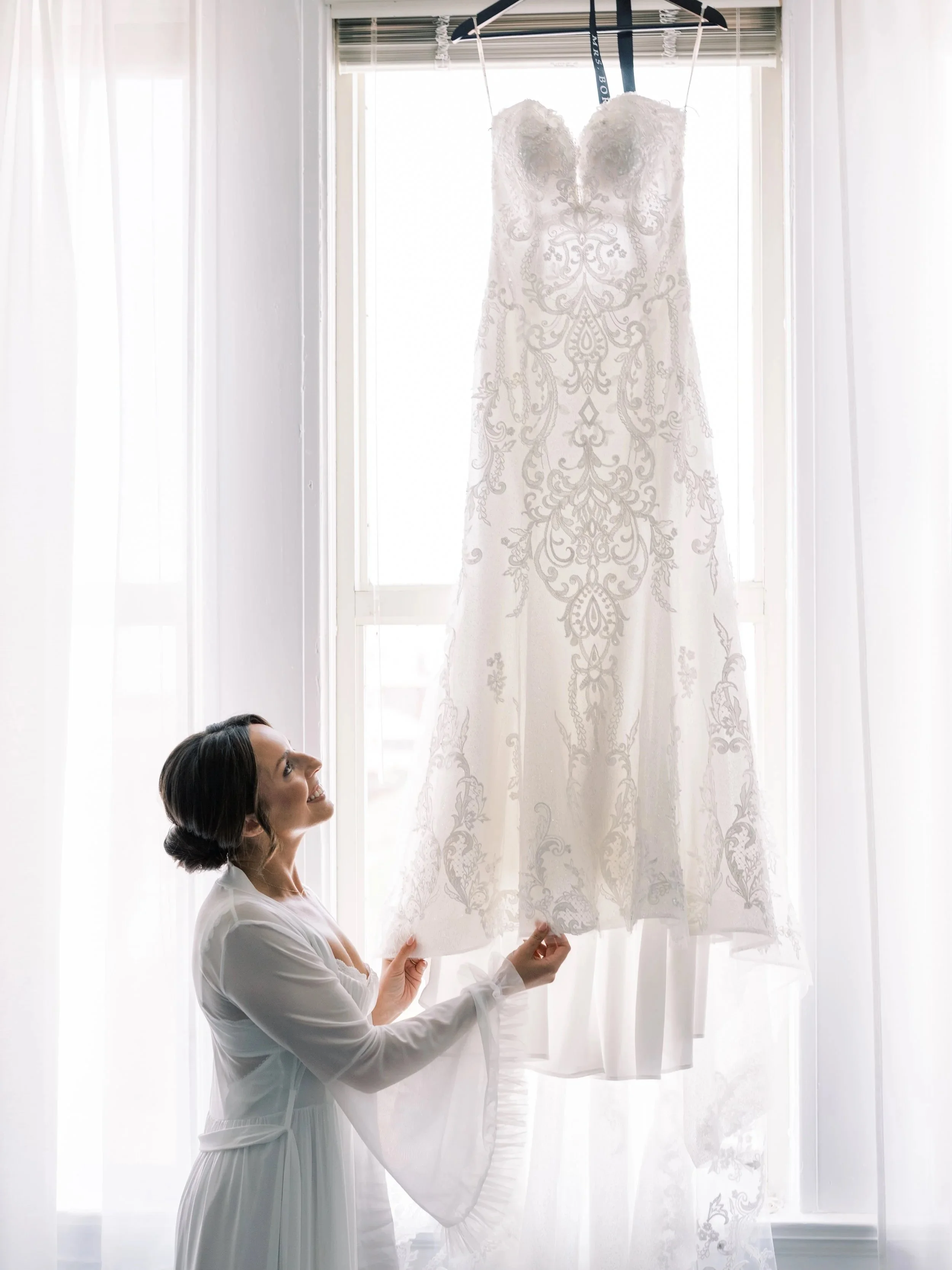 Bride admiring her dress hung up in Tower Suites, bridal getting ready area.