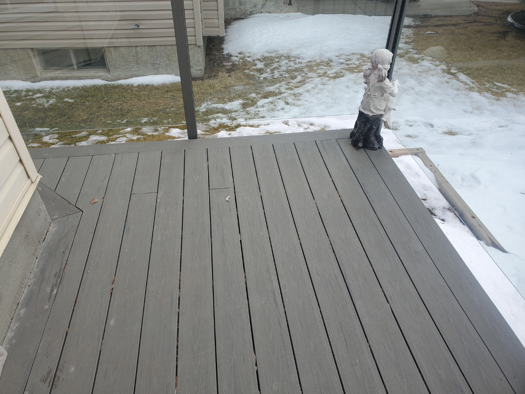 Backyard deck with a decorative statue of a girl and a dog looking out over a snowy yard.