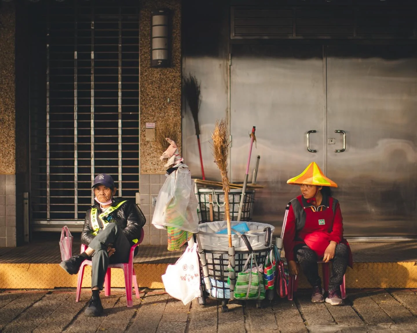 Beneath a patient sun ☀️,
they borrow a moment from the road&mdash;
hands at rest, brooms standing guard,
as the city 🌆 exhales
and lets its heartbeat soften.

📍Taipei 台北，Taiwan 台灣 🇹🇼

#taipeitravel #taiwanstreetphotography #taiwan🇹🇼 #台北 #stree