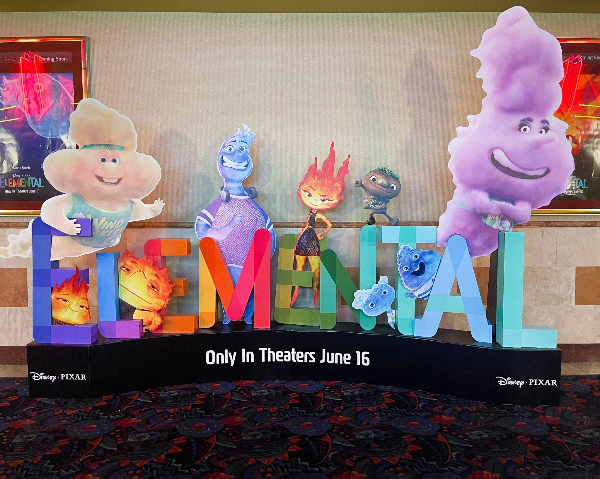 Colorful promotional display for the Disney Pixar animated film 'Elemental' featuring cartoon characters representing fire, water, and other elements, with text indicating the movie's release date of June 16.