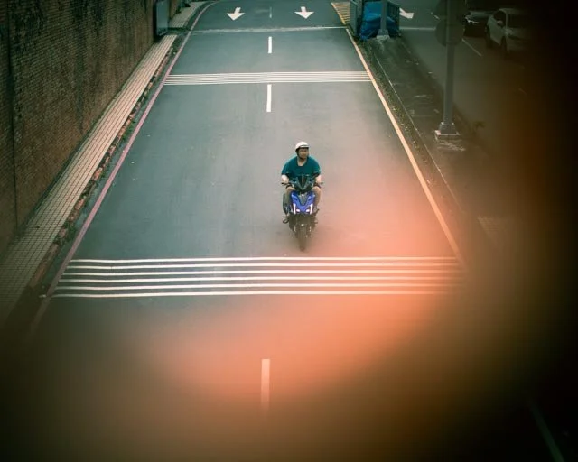 俯瞰空蕩街道上一名機車騎士駛過條紋路面標線，台灣